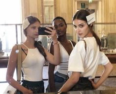 three young women standing in front of a counter taking a photo with their cell phone