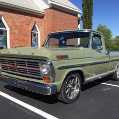 an old green truck parked in front of a brick building