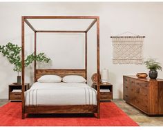 a bed sitting in the middle of a room next to a dresser and table with a potted plant on it