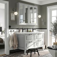 a white bathroom with black and white checkered flooring, two mirrors on the wall