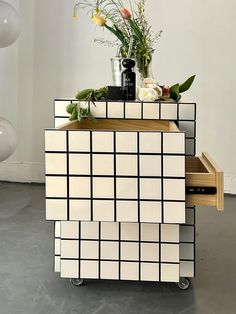 a white and black checkered cabinet with flowers on top