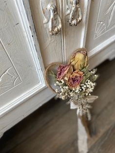 a bouquet of flowers sitting on top of a wooden floor next to a white cabinet