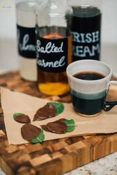 a cup of coffee sitting on top of a wooden cutting board next to two bottles