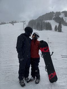 two people standing in the snow with their snowboards