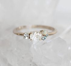 three stone ring on top of clear crystal rock with white and blue stones in the middle