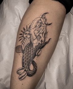 a woman sitting on top of a mermaid tattoo