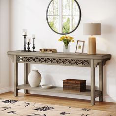 a console table with vases and candles on it next to a round mirror in a room