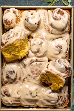 a pan filled with cinnamon rolls covered in icing