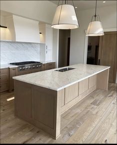 a kitchen with an island and two pendant lights hanging from it's ceiling over the sink