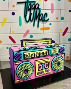 a pink boombox sitting on top of a table next to a wall with colorful confetti