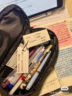 a black case filled with lots of different types of pens and writing materials on top of a wooden table