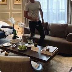 a man standing in the middle of a living room next to a couch and coffee table