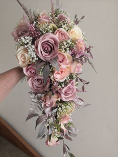 a bridal bouquet with pink roses and baby's breath in the center is being held by someone