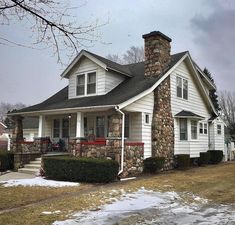 a white house with a stone chimney in the front yard