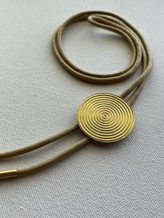 Golden brass Inner Circles bolo tie necklace on light gold colored nylon cord. Adjustable Brass Lariat Necklace As Gift, Modern Gold Jewelry With Sliding Knot, Gold Lariat Jewelry With Sliding Knot, Gold Necklace With Adjustable Sliding Knot, Gold Metal Jewelry With Sliding Knot, Adjustable Gold Bolo Tie As Gift, Adjustable Gold Jewelry With Cord, Adjustable Gold Necklace With Sliding Knot, Gold Lariat Necklace With Adjustable Cord