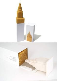 an open white box with gold foil on the inside and outside, next to a small tower