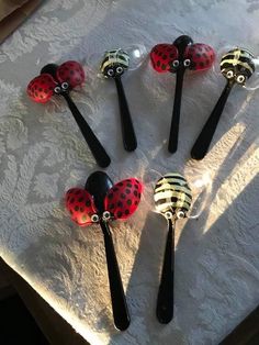 six spoons with ladybug designs on them sitting on a white tablecloth