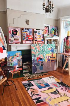 an artist's studio with various paintings on the wall and wooden flooring,