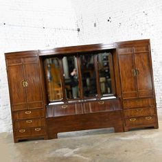 a large wooden cabinet with mirrored doors on it's sides and drawers in the middle