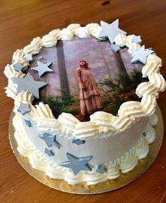 a white cake with silver stars and a photo on the top is sitting on a wooden table