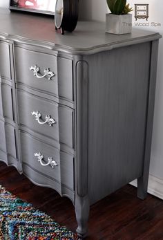 an old dresser is painted gray with silver paint