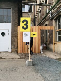 a yellow and white street sign sitting on the side of a road next to a building