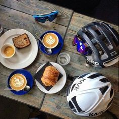 a table topped with plates of food and cups of coffee next to a bicycle helmet