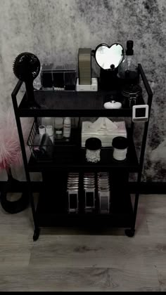 a shelf with various items on it in front of a wall covered in black and white paint