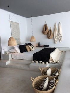 a bedroom with white walls and lots of pillows