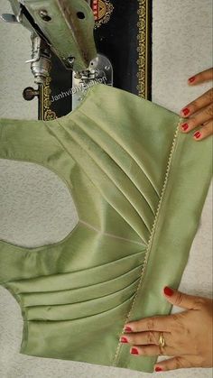 a woman's hand is holding the back of a green dress with zippers