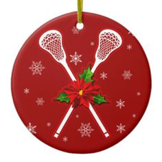 a christmas ornament with two lacrosse sticks and poinsettis on it