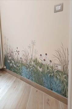 a wall with flowers and grass painted on it's side, next to a wooden floor