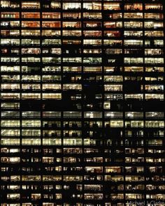 many windows are lit up at night in the building's dark colors and patterns