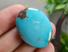 a person holding a turquoise stone in their left hand with dirt on the inside of it