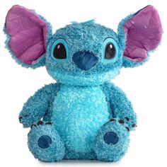 a blue stuffed animal with big ears sitting on top of a white surface and looking at the camera