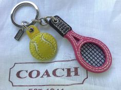 a tennis racquet and ball keychain on a white tablecloth with the coach logo