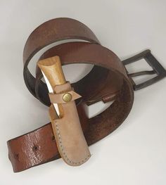 a leather belt with a wooden buckle on the bottom and two different colored belts attached to it