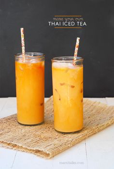 two glasses filled with orange juice sitting on top of a table next to each other