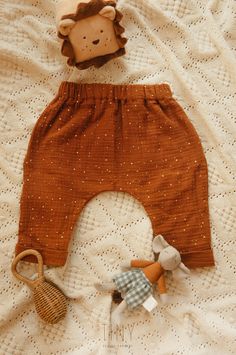 two stuffed animals are laying on a white bed with an orange pant and brown pants