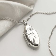 "This sterling silver oval locket, makes a wonderful keepsake, and memorable gift.  The front features a beautiful floral design and the back is blank, ideal for engraving a name, date or short message. The perfect sentimental gift for a friend or loved one. So why not make this a truly personal gift by having your own special message engraved, by us, on this eye catching locket. To order this locket simply select the chain length and the font you would like us to use from the drop down menus, you can select \"no engraving\" if you would like us to leave it blank. Then at the checkout enter the message you would like us to engrave in the \"note to seller\" box. Ideally 30 characters fits best on this locket. Both the locket and the chain are made from sterling silver. The locket measures 3 Silver Oval Jewelry With Birth Flower Detail, Silver Oval Jewelry With Birth Flower, Silver Locket Necklace With Birth Flower Round Pendant, Oval White Gold Locket Necklace For Keepsake, White Gold Oval Locket Necklace For Keepsake, Oval White Gold Locket Necklace Keepsake, Silver Oval Locket Necklace Keepsake, Silver Locket Necklace With Birth Flower For Anniversary, Silver Wedding Locket Necklace With Birth Flower