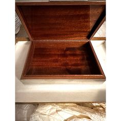 an open wooden box sitting on top of a bed