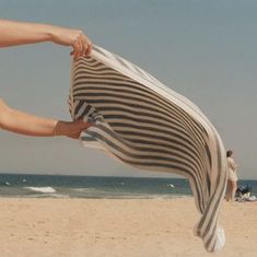 a person is holding up a towel on the beach