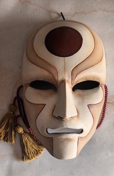 a white mask with a brown face and tassels hanging from it's sides