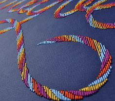 a close up of a colorful beaded pattern on a blue surface with the word love spelled in it