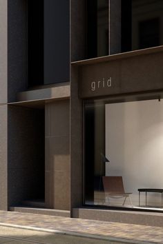 an empty chair sitting in front of a window on the side of a building that says grid