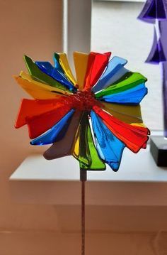 a multicolored pinwheel on a stick in front of a window