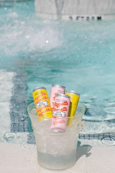 four cans of water in a bucket next to a swimming pool