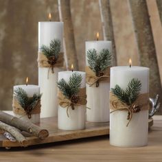 white candles with pine cones and burlocks wrapped in twine on a wooden tray