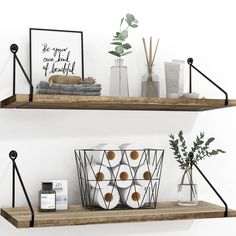 two wooden shelves with black metal brackets and white vases on them, one holding candles