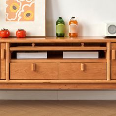 a wooden entertainment center with drawers and bottles on it's sideboard next to a painting